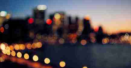 ADHD Essentials: 8 Therapist-Guided Tips for Thriving with Your ADHD Brain 1 Blurred city skyline at dusk with colorful bokeh lights, reminiscent of the vibrant and abstract atmosphere that inspires focus in ADHD Essentials, where buildings and streetlights meld into a dreamy vision.
