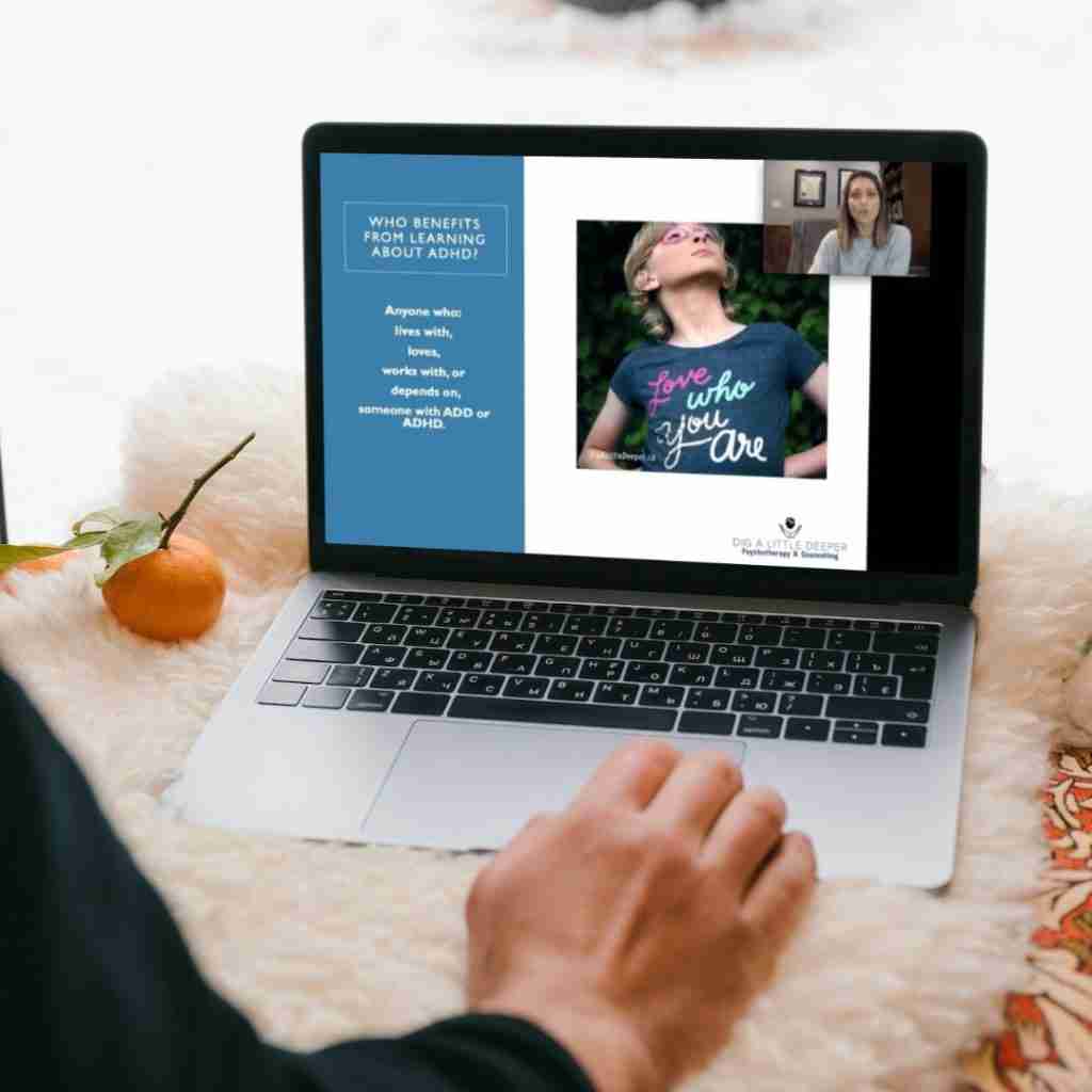 Sitting comfortably with a laptop on a fluffy surface, someone participates in a video call discussing ADHD-adapted psychotherapy supervision. Onscreen, two individuals dive into a presentation about effective techniques. Nearby, a mandarin and plant bring a touch of nature to the workspace.